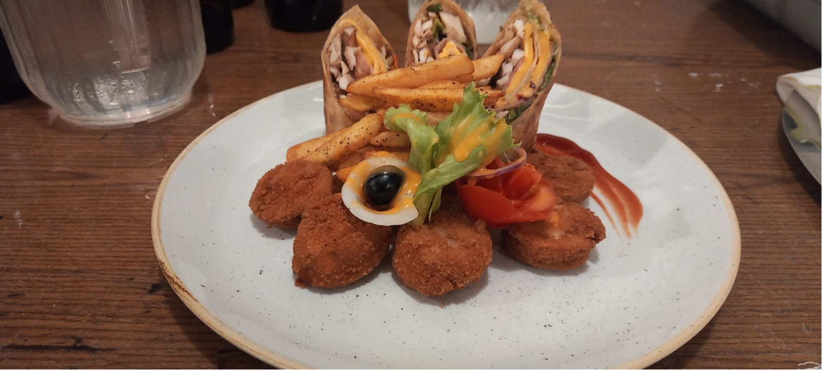 Wrap meal plated with fries and crispy bites on a white plate.