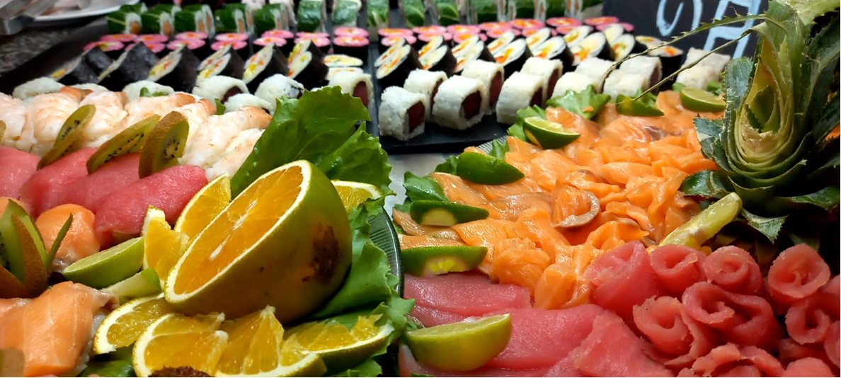 Sashimi and sushi display with salmon, tuna roses, kiwi, and citrus.