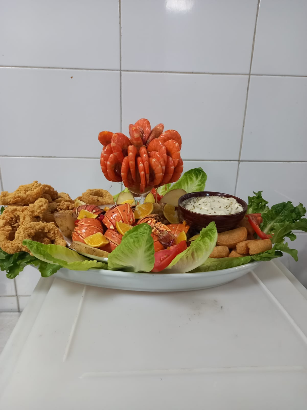Seafood platter with fried items, lobster, shrimp tower, and dipping sauce.