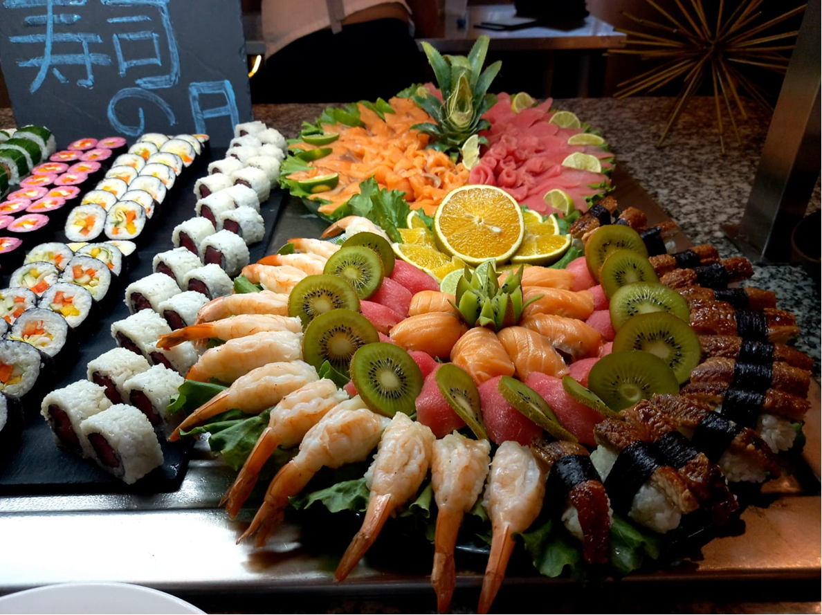 Elaborate sushi and sashimi platter with shrimp, tuna, salmon, eel, and fruit.