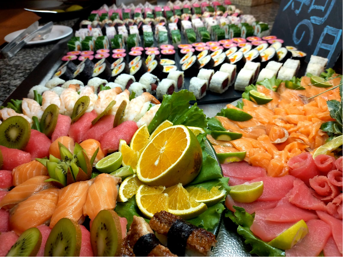 Close-up sushi and sashimi spread with citrus, salmon, tuna, and rolls.
